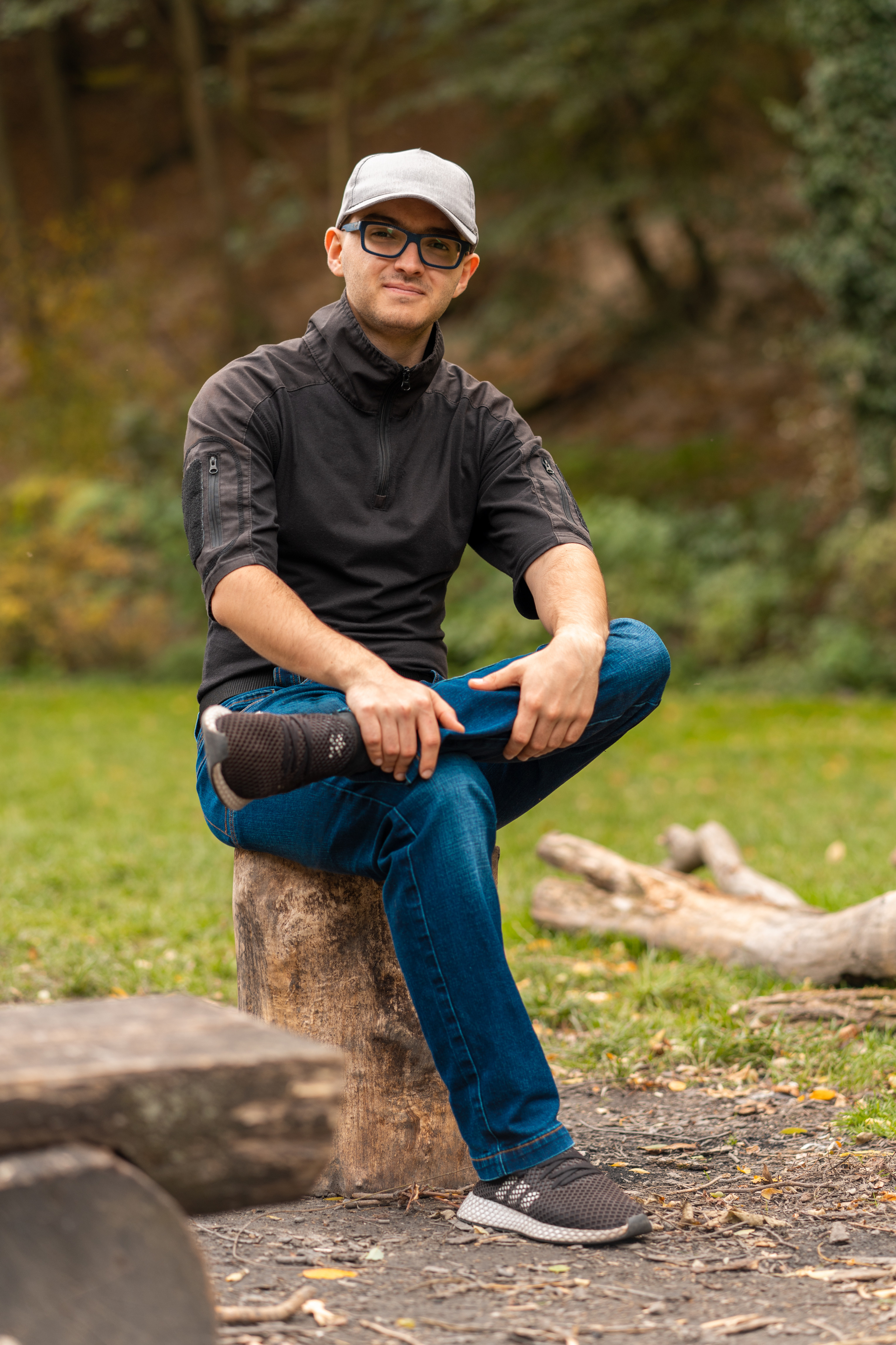 a young man sitting on a tree trunk.